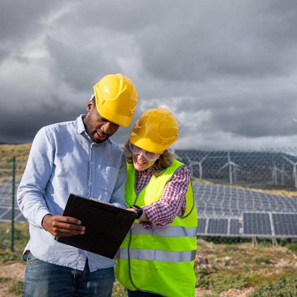 Two colleagues consult documents while at a photovoltaic power station.
